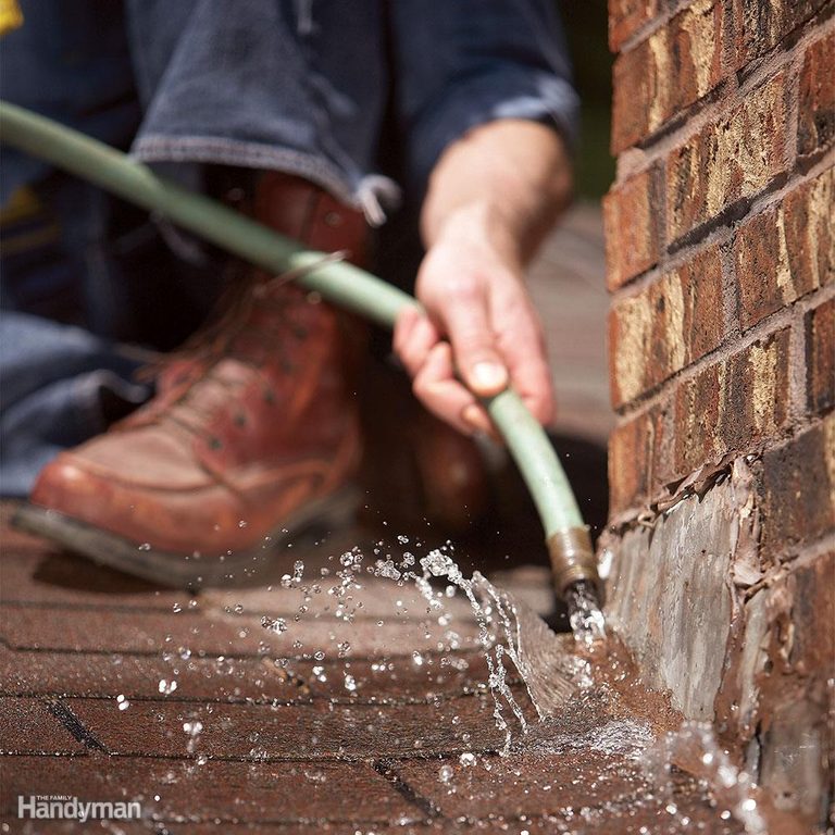 A person is using a long handled tool to remove the brick.