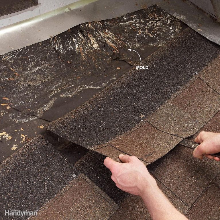 A person cutting the shingles off of a roof.