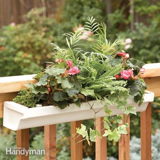 A balcony planter with plants and flowers on it.