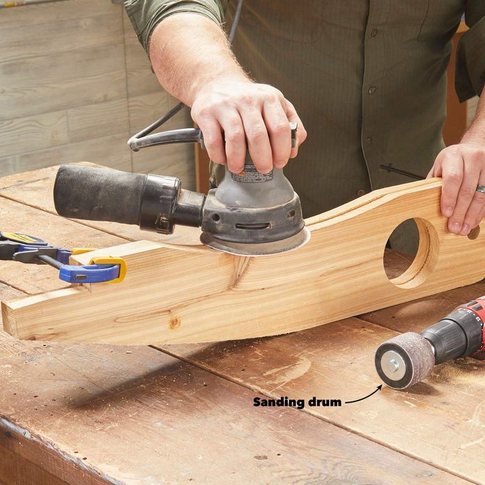 A person sanding down some wood with a power tool.