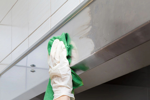 A person wearing green gloves cleaning the outside of a building.