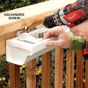 A person using a drill to attach the railing.