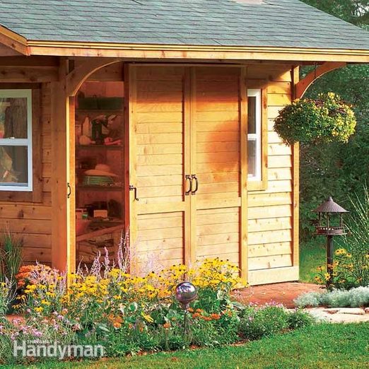 A garden shed with flowers and plants in the yard.