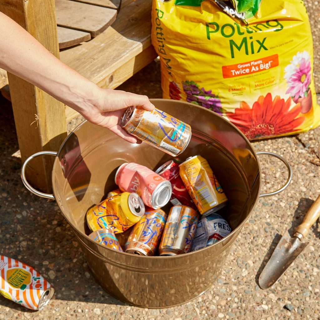 A person is putting cans of soda in a bucket.