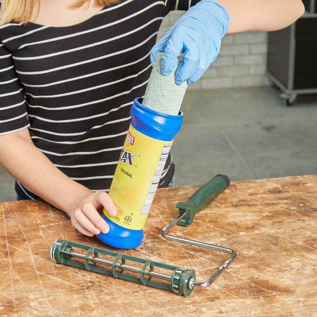 A woman holding a roller with paint on it.