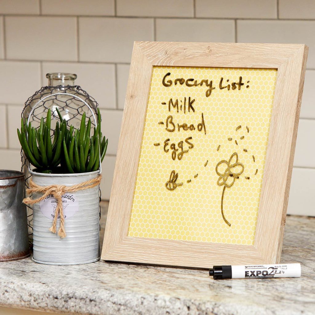 A picture frame with a grocery list written on it.