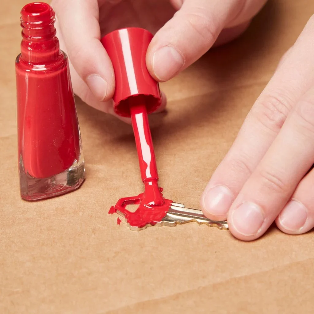 A person is putting red nail polish on the tip of their finger.