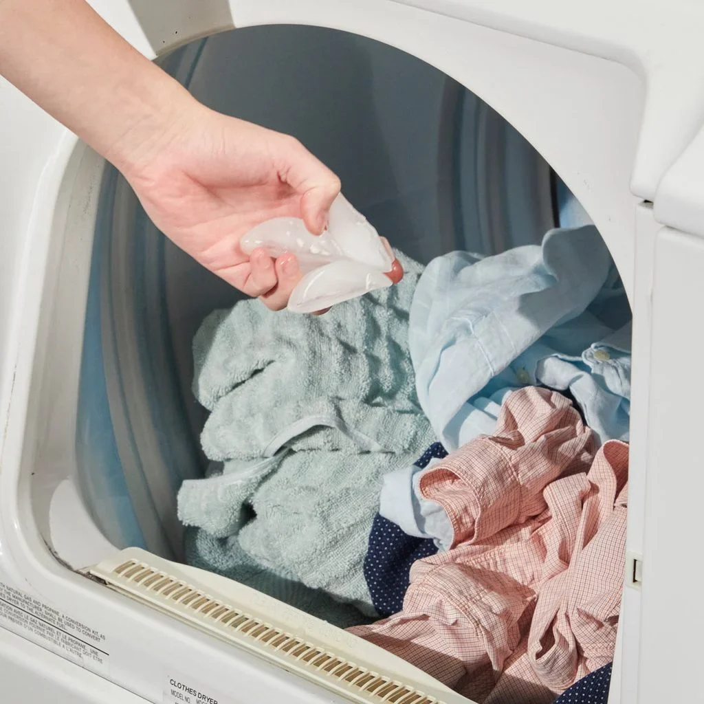 A person is putting clothes in the dryer.