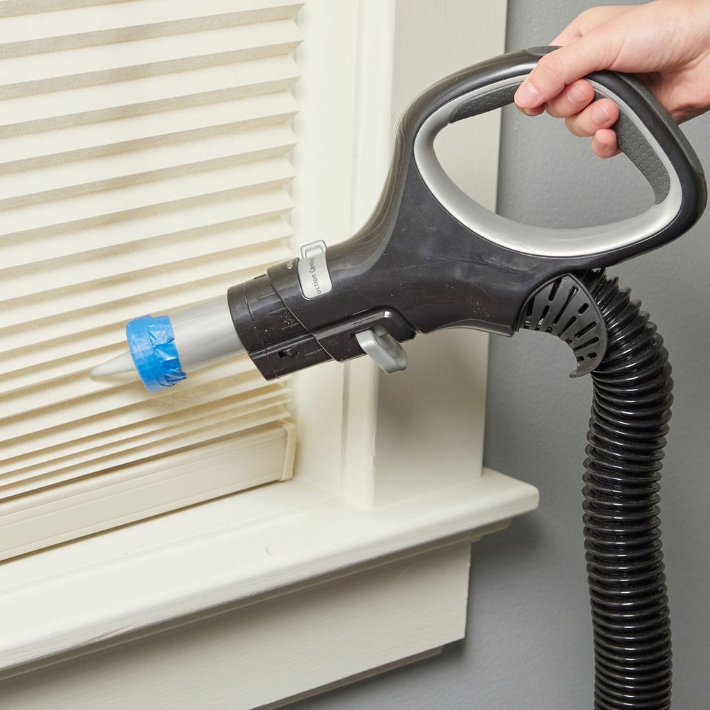 A person using an air duster on a window.