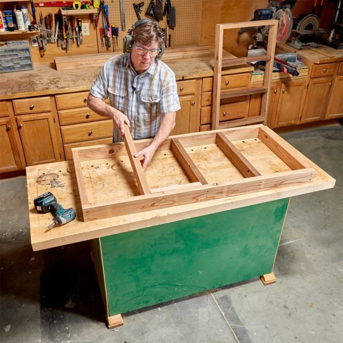 A woman in plaid shirt working on wooden table.