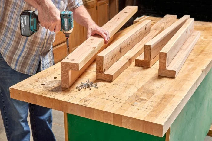 A man using a drill to make wooden beams.