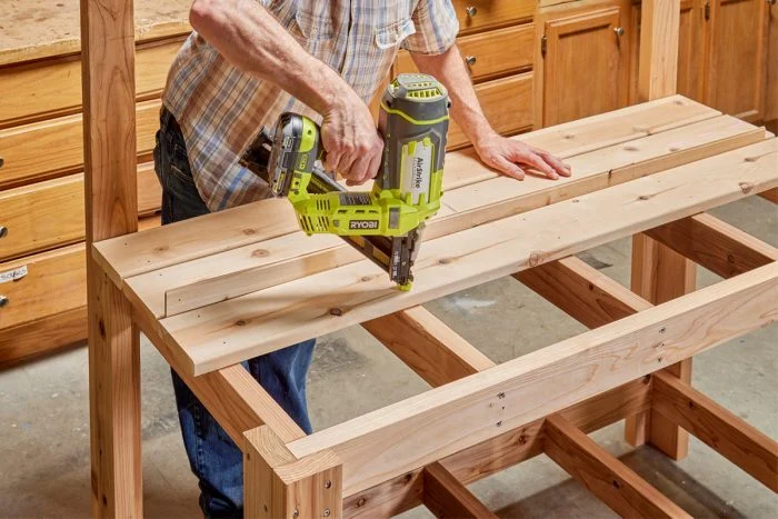 A man using a drill to build a wooden table.