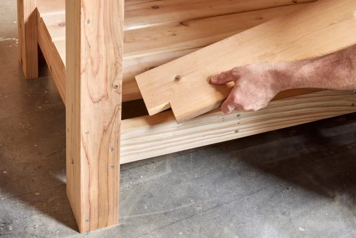 A person holding onto the wood of a bench