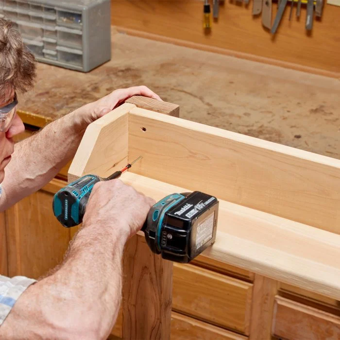 A man using a drill to make something out of wood.