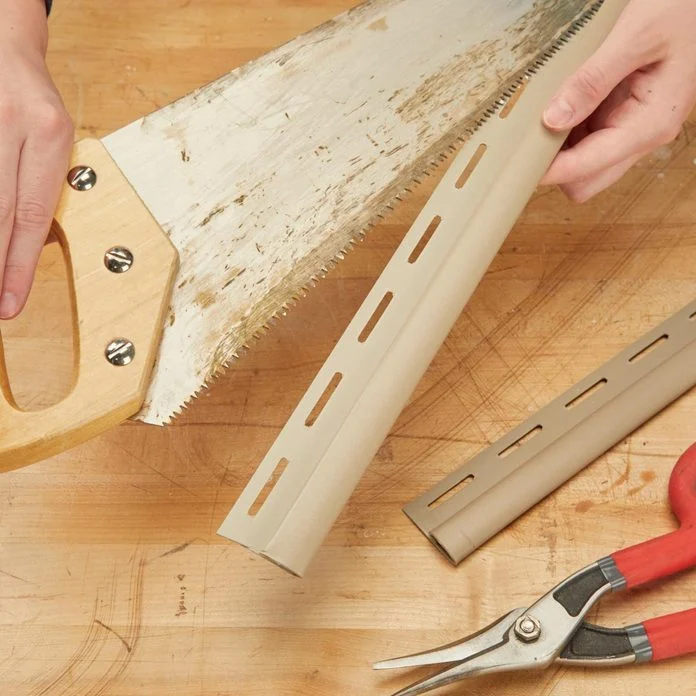 A person holding a saw and some other tools