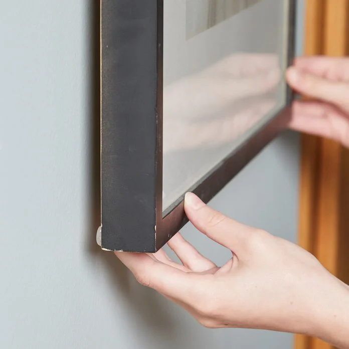 A person holding onto the frame of a television