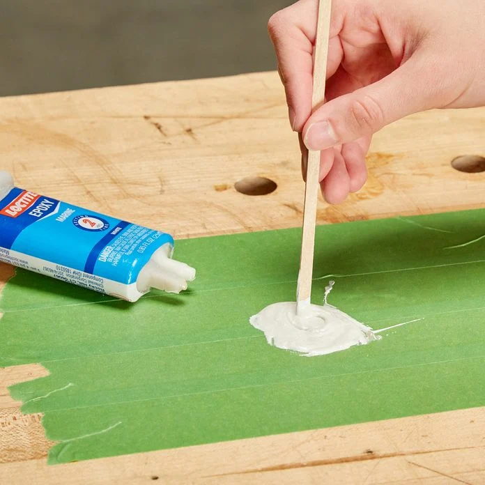 A person painting on the side of a green board.