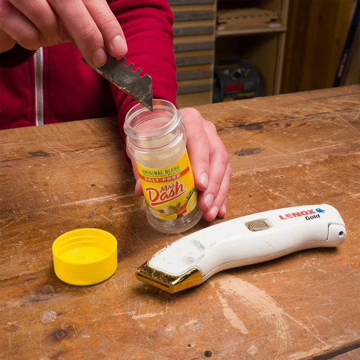 A person is holding a jar and a hair trimmer.