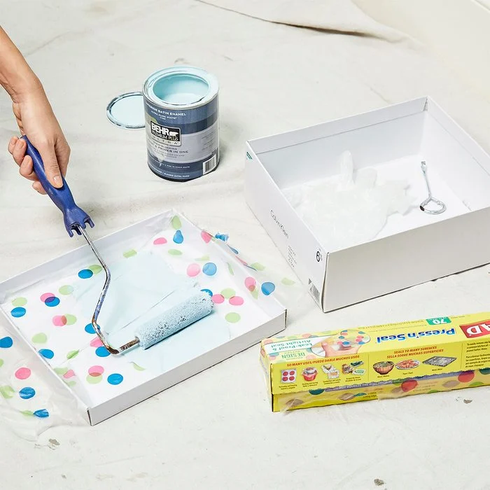 A person painting a cake with blue paint.