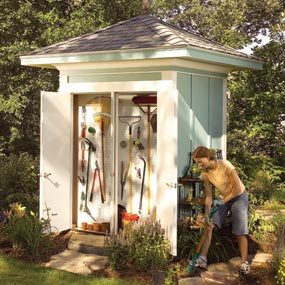 A man is working on the side of a shed.