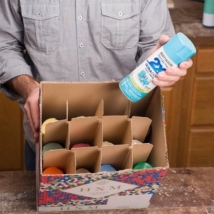 A man holding a box of eggs and spray paint.