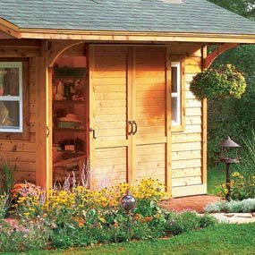 A wooden shed with flowers growing in the front.