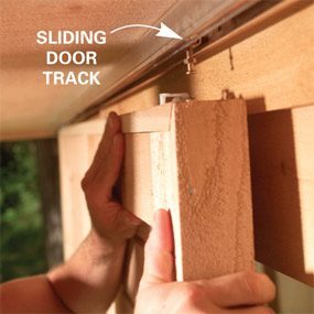 A person holding onto the door track of a sliding garage door.